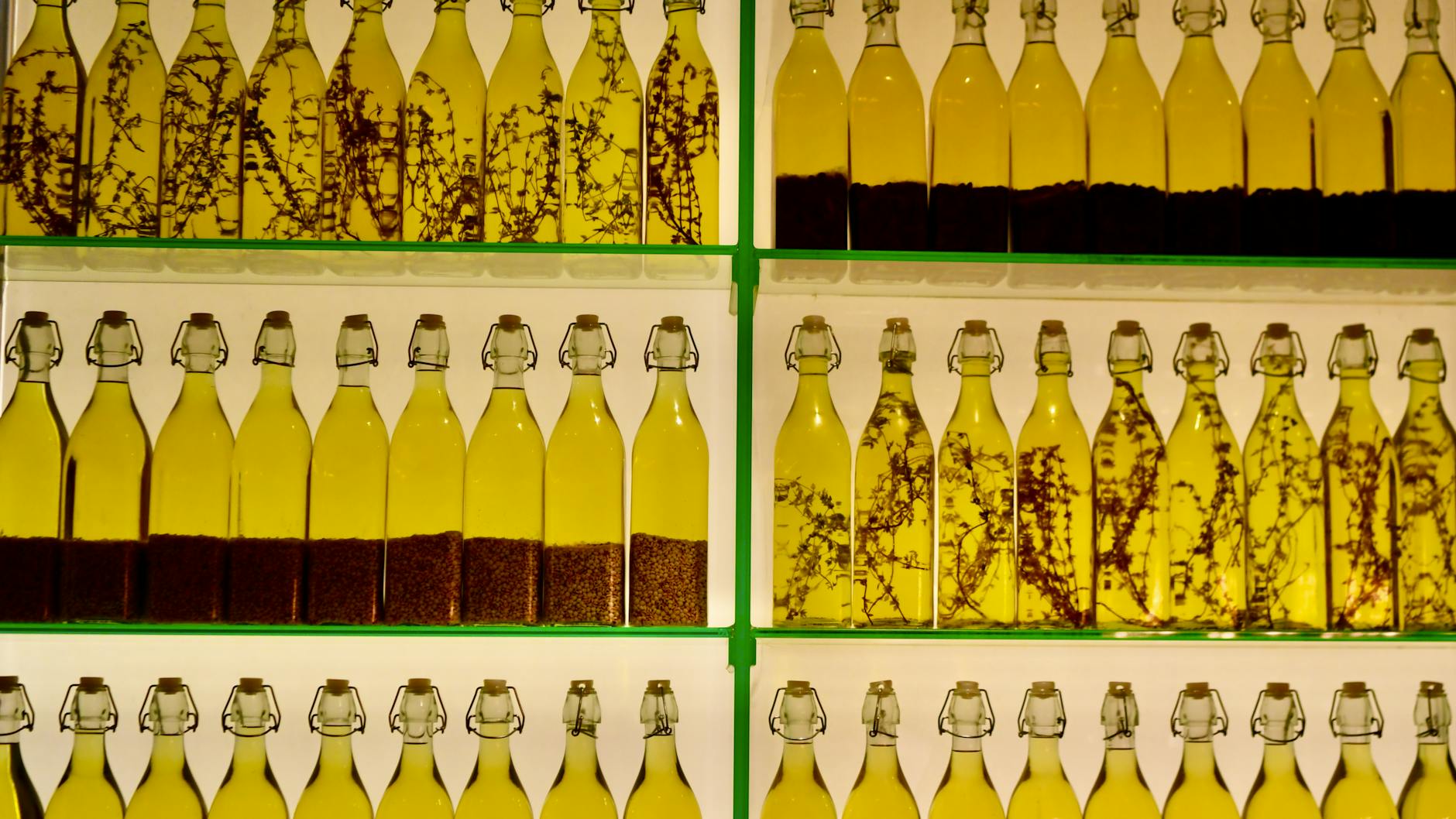 Butelki oliwy z oliwek z ziołami ustawione w rzędach na półkach