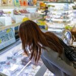 Młoda kobieta wybiera produkty w alejce japońskiego sklepu spożywczego
