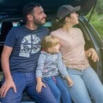 Rodzina siedzi w bagażniku auta podczas przerwy w podróży po Europie