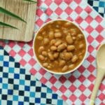 Miska pieczonej fasoli z łyżką na kolorowej kraciastej serwecie