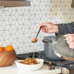 Osoba gotuje jednogarnkowe danie w nowoczesnej kuchni z warzywami