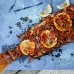 Pieczona ryba po grecku z cytryną na niebieskim półmisku