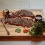 Pokrojony grillowany stek z zielonym pesto na drewnianej desce