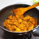 Patelnia z złocistym curry z kurczakiem gotującym się na kuchence