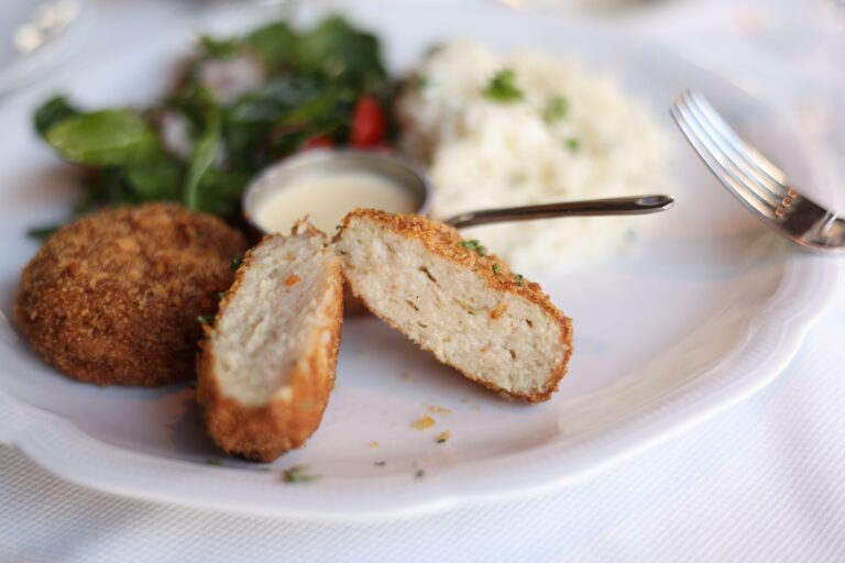 Panierowany kotlet z ryżem, sałatką i sosem na talerzu