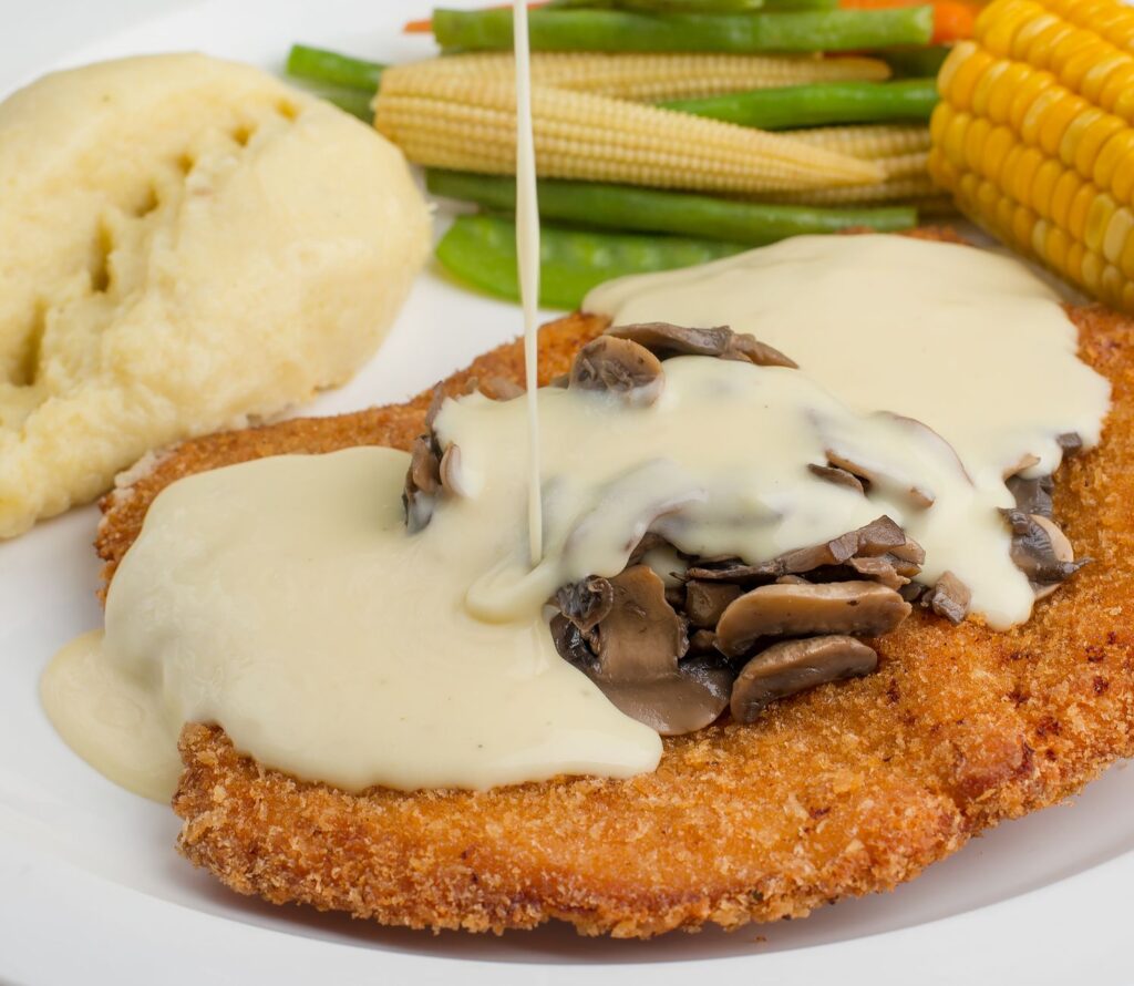 Panierowany kotlet z sosem pieczarkowym i świeżymi warzywami